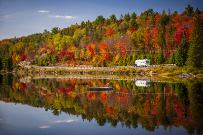 Autumn colours in Canada with a lakeside forest and RV driving along the shoreline, a classic scene on Canada & New England cruise holidays