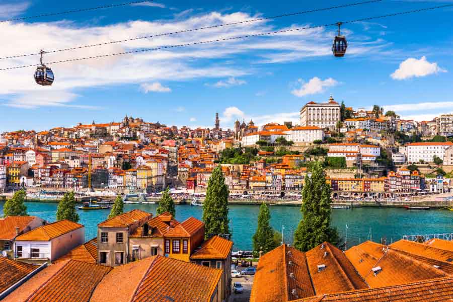 Panoramic view of Porto across the Douro River with colourful riverside buildings and cable cars